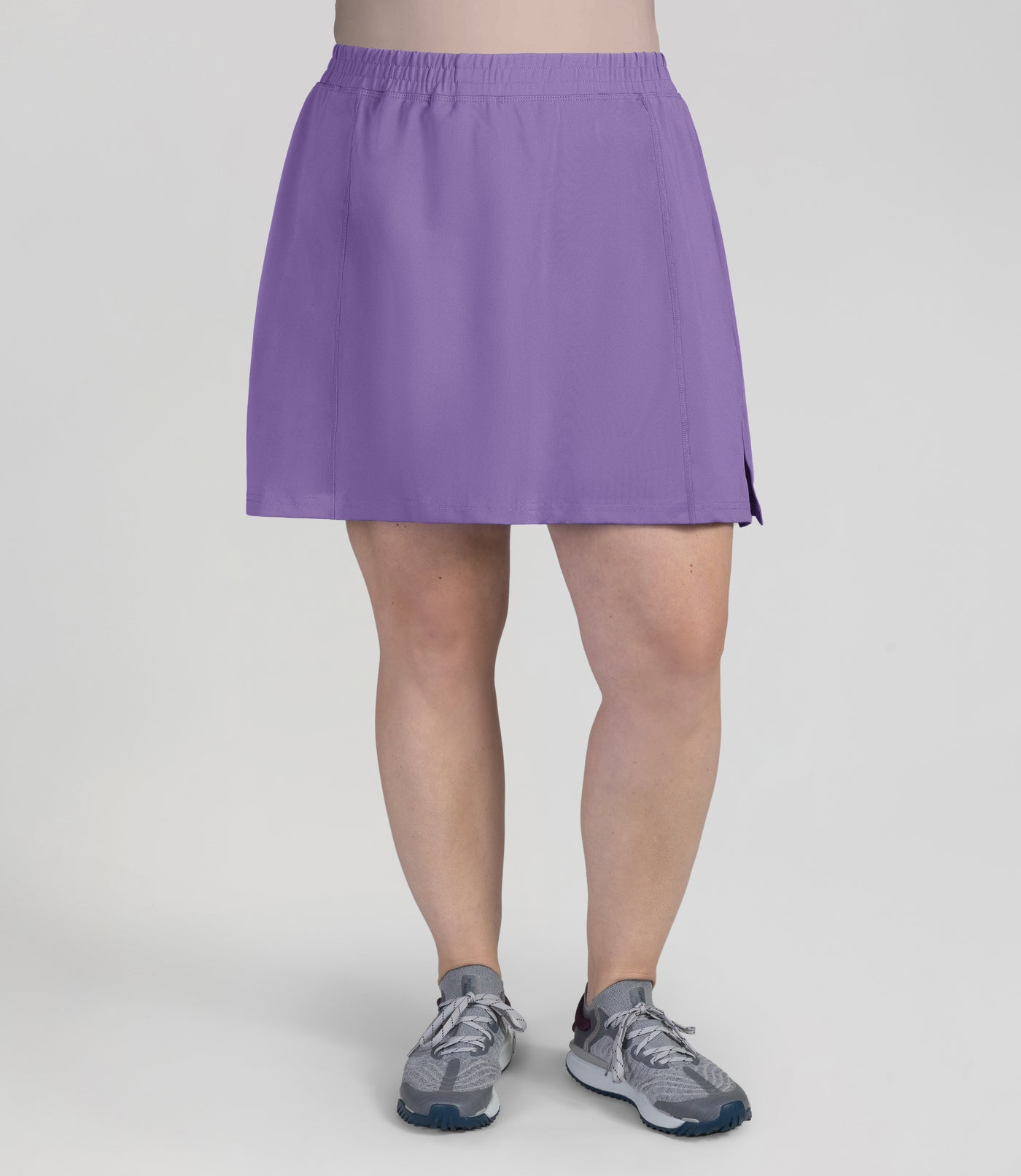 Bottom half of plus sized woman, front view, wearing JunoActives Quikwik lite skirted short in color iris. Skirt hem is a few inches above knee.