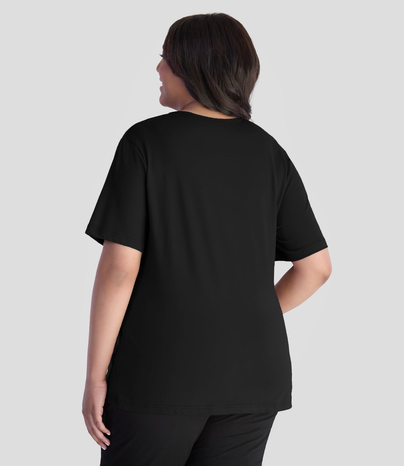 JunoActive model wearing EasyLuxe Classics V-Neck Plus Size Top in color black . Model is facing back with her left arm by her side and right hand on hip.
