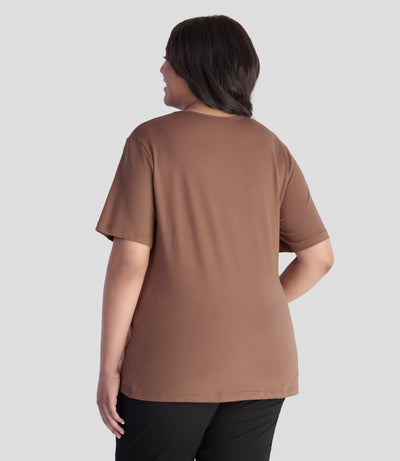JunoActive model wearing EasyLuxe Classics V-Neck Plus Size Top in color cafe latte. Model is facing back with her left arm by her side and right hand on hip.