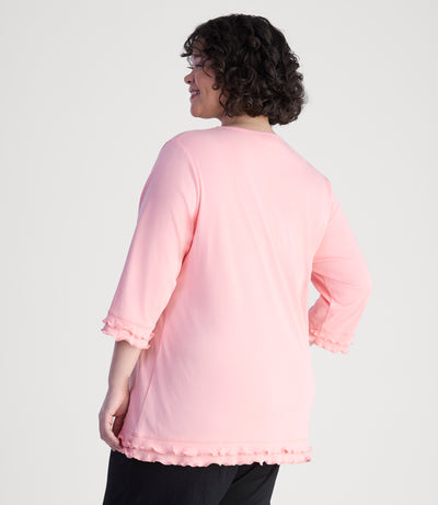 Model, facing back, wearing cotton chic lettuce trim 3-4 sleeve plus size top in color peach blossom.
