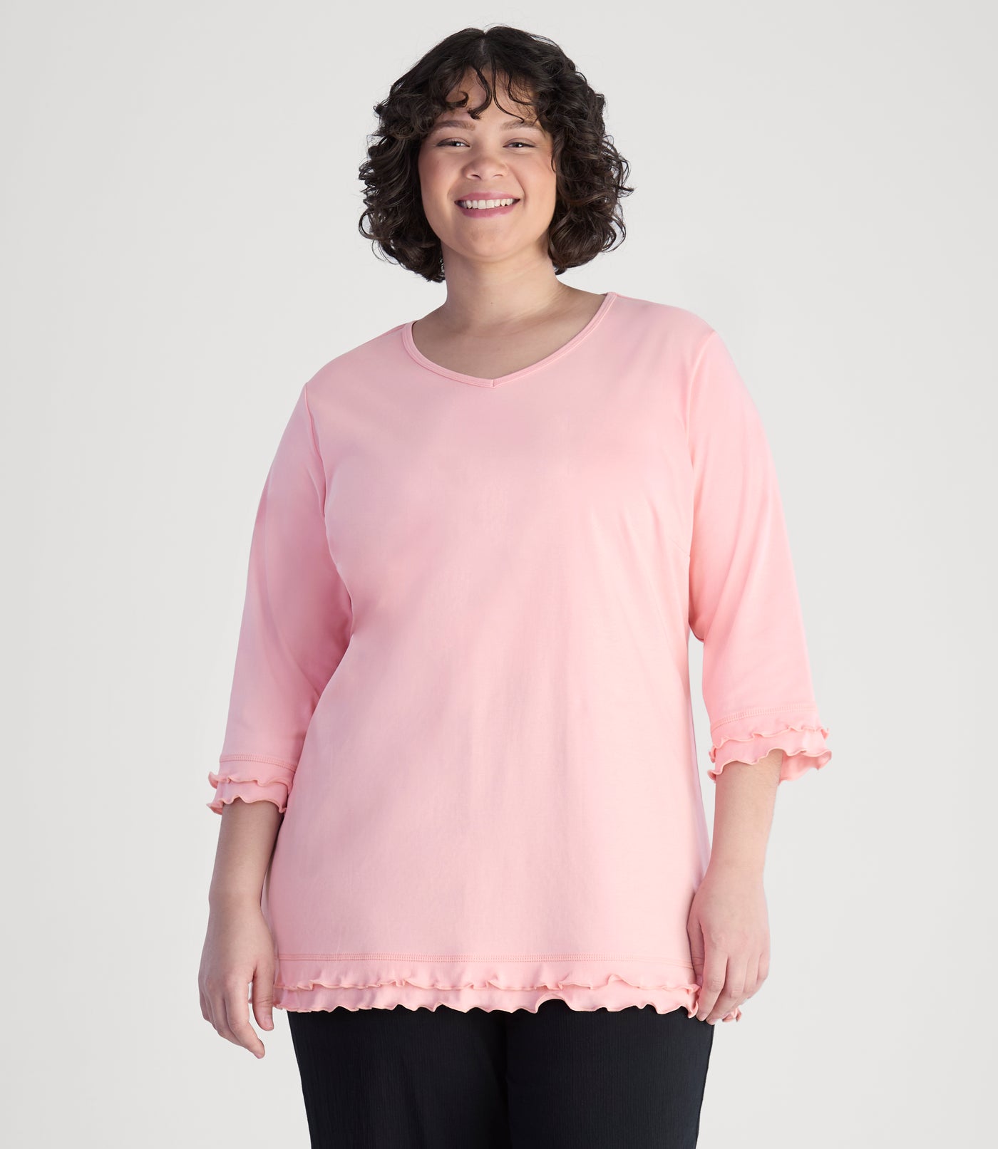 Model, facing front, wearing cotton chic lettuce trim 3-4 sleeve plus size top in color peach blossom.