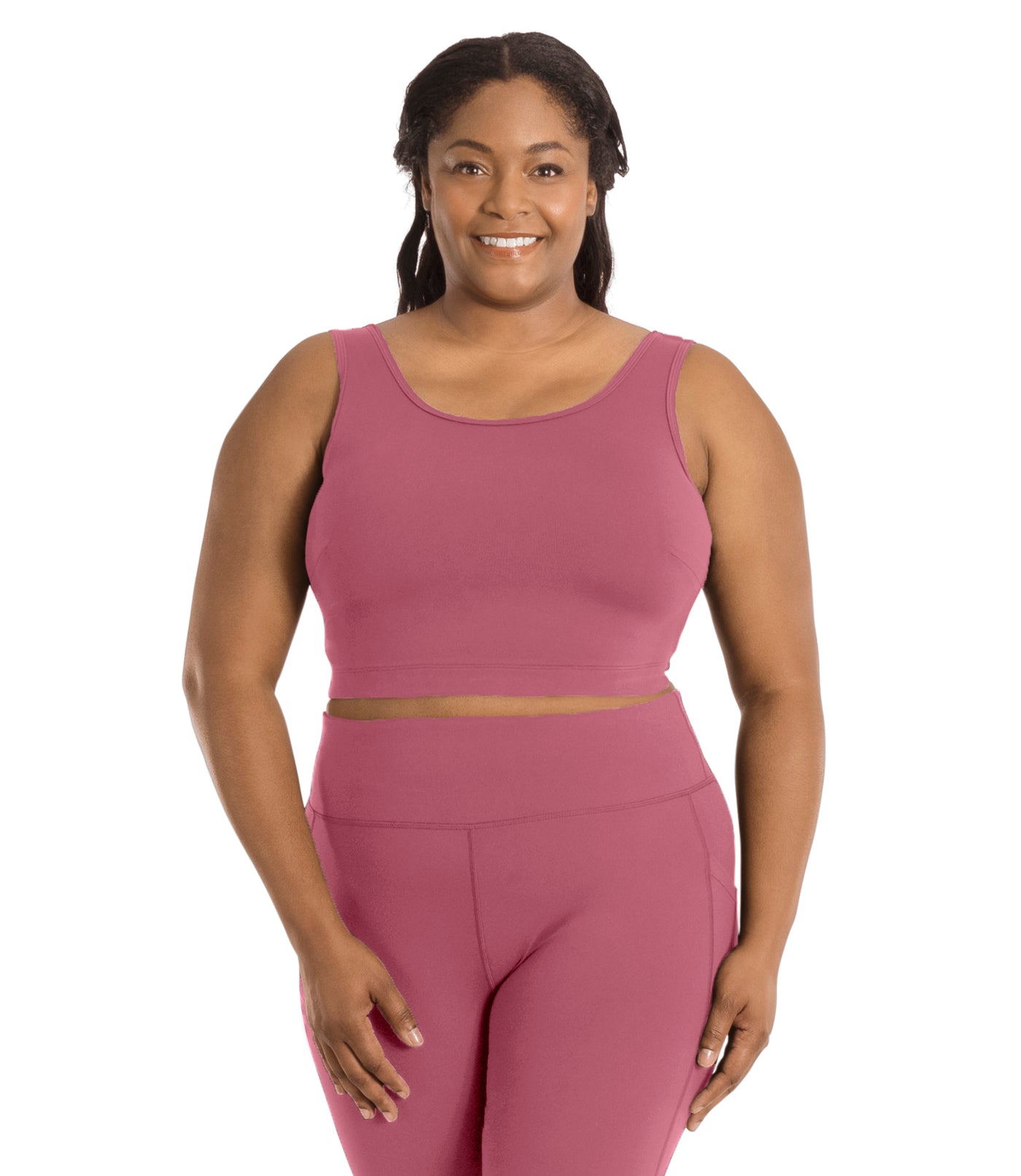 Plus size woman, facing front, wearing JunoActive plus size JunoStretch Scoop Bra in mauve. The woman is wearing black plus size JunoActive leggings. Her arms fall naturally to her side with her hands on her thighs.