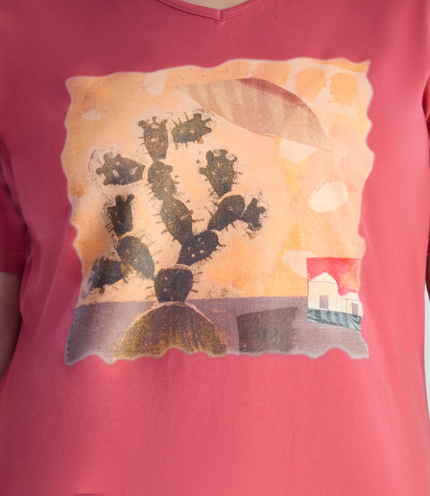 Close up of model wearing JunoActive's designer graphic v-neck top in rosy red. Printed is a Sedona scene with cactus, a house in the background and lovely warm colors with unique texture.