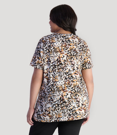 Model, facing back, wearing JunoActive's Junonia Lifestyle printed short sleeve neck top in color natural melange.