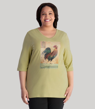 Model is wearing JunoActive's designer graphic 3/4 sleeve v-neck tunic in color aloe green. Print has a rooster on it with unique paint brush texture.