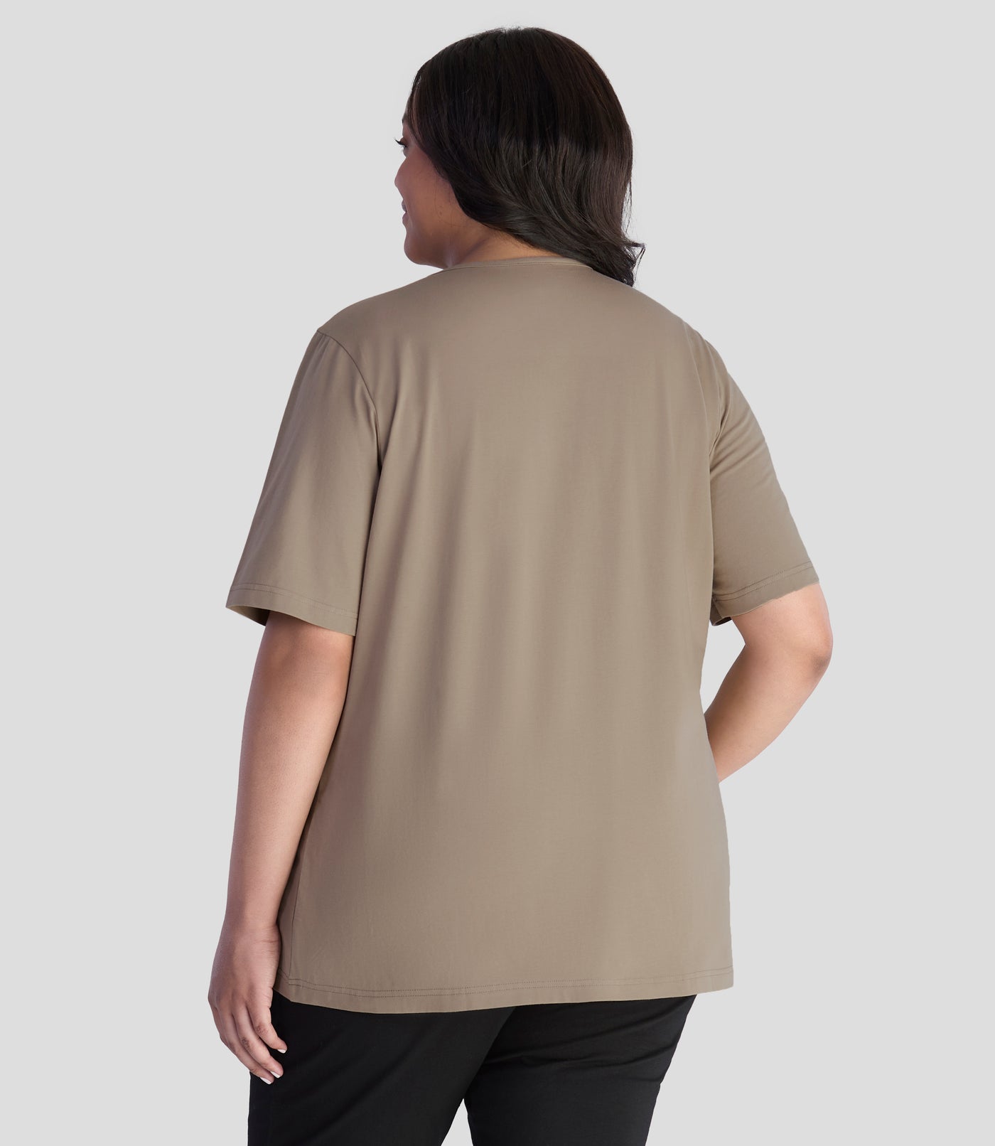 JunoActive model, wearing Stretch Naturals Lite Pintuck Top in color Beachwood. Model is facing back and hands down by her side.