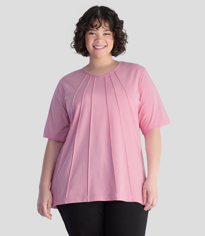 JunoActive model, wearing Stretch Naturals Lite Pintuck Top in color peony pink. Model is facing front and hands down by her side.