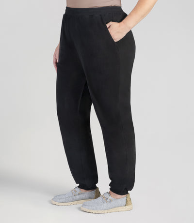 JunoActive model facing front, wearing Legacy Cotton Casual Pocketed pant in color black. Her left hand is in her pocket and right arm falling by her right side. Pants fall at ankles with loose cuff.