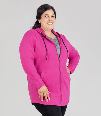 Model facing front, wearing JunoActive's MaVie Zip Front Hoodie in Magenta Pink. Left hand on hip and right hand dropped on thigh.