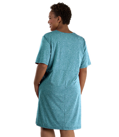 Plus size woman ,facing back looking left, wearing JunoActive plus size SoftWik Short Sleeve Dress in the color Heather Ocean. Her left hand is in the dress pocket. The dress length hits at her knee.