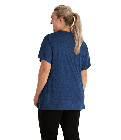 Plus size woman, facing back looking to the left, wearing JunoActive plus size QuikLite V-Neck Short Sleeve top in the color Heather Blue. She is wearing JunoActive Plus Size Leggings in the color black. 