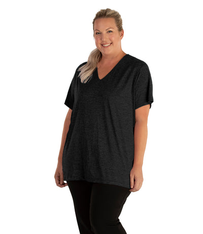 Plus size woman, facing front, wearing JunoActive plus size QuikLite V-Neck Short Sleeve top in the color Heather Black. She is wearing JunoActive Plus Size Leggings in the color black. 
