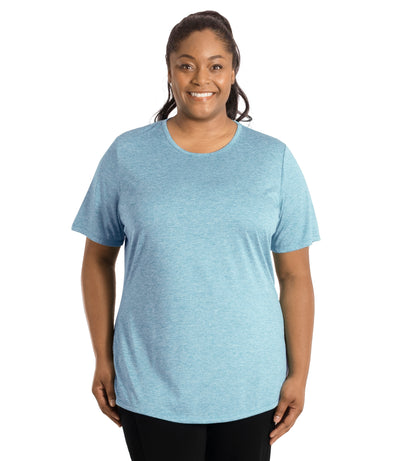 Plus size woman wearing JunoActive's SunLite Scoop Neck  front view wearing black pants and hands by side in heather light blue.