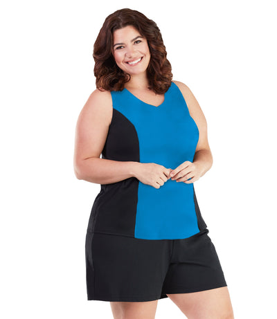 Plus size woman, facing front, wearing AquaSport Tankini Top Pacific Blue and Black. The front of the tankini has a rounded v-neck with princess seam color blocking in black. Solid blue color on the core of the top. 