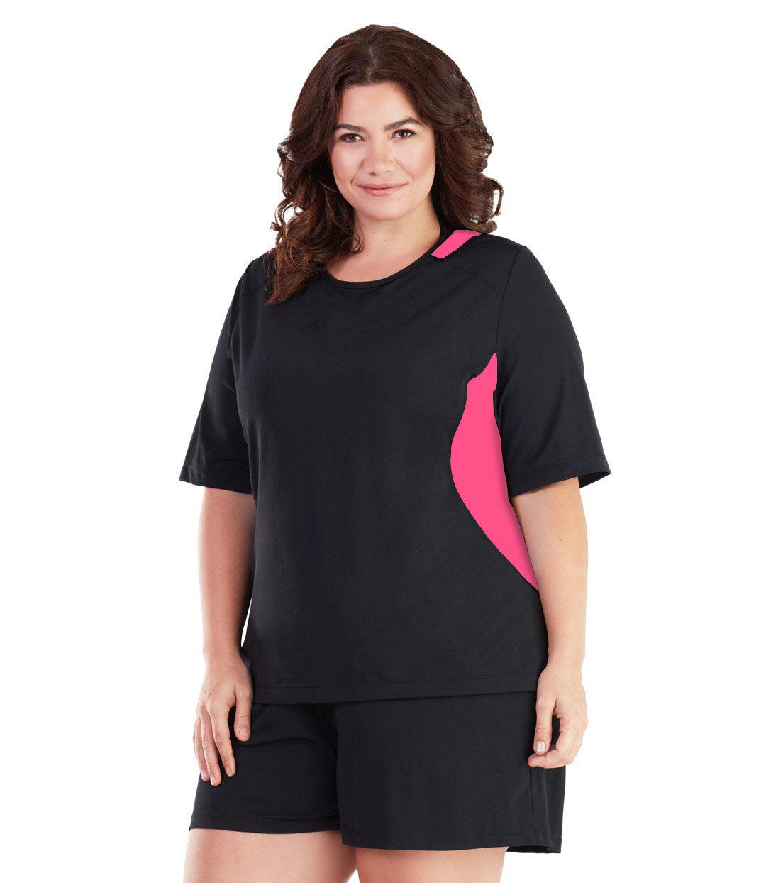 Plus size woman, facing front, wearing AquaSport Colorblock Swim Tee Pink and Black. Pink colorblocking on waist and shoulders. Long cover short sleeves meeting at the elbow and a rounded neckline. 