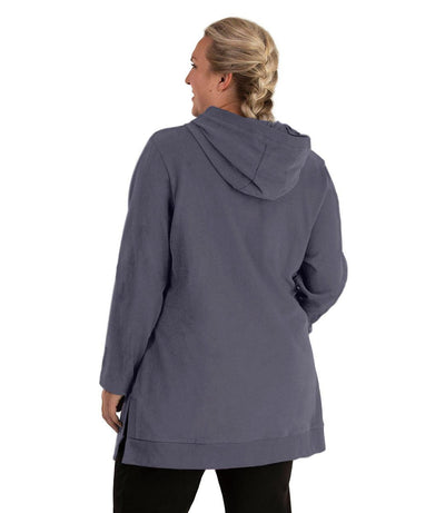 Plus size woman, facing back looking left, wearing JunoActive plus size Legacy Cotton Casual Pullover V-Neck Hoodie in the color Misty Grey. She is wearing JunoActive Plus Size Leggings in the color Black.