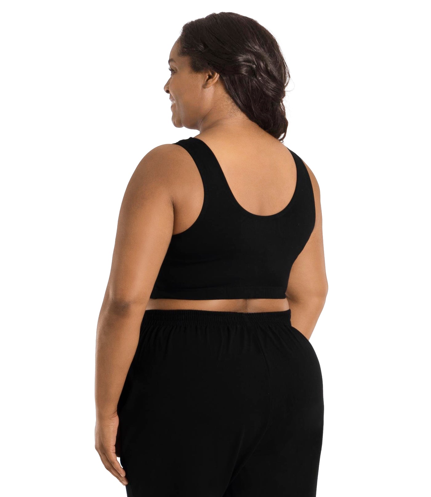 Plus size woman, facing back, wearing JunoActive plus size Stretch Naturals Scoop Neck Bra in black. The woman is wearing black JunoActive plus size bottoms. Her arms fall naturally to her side.