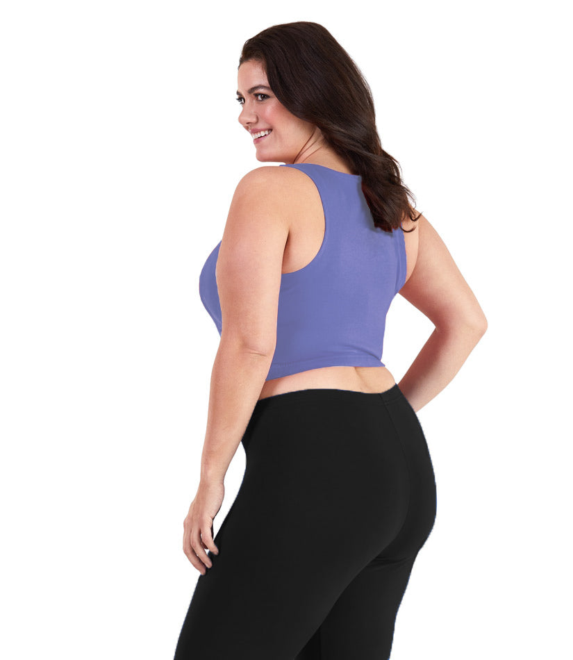 Plus size woman, facing back, wearing JunoActive plus size Stretch Naturals V-Neck Bra top in Cornflower Blue. The woman is wearing black JunoActive plus size leggings. Her arms fall naturally to her side.