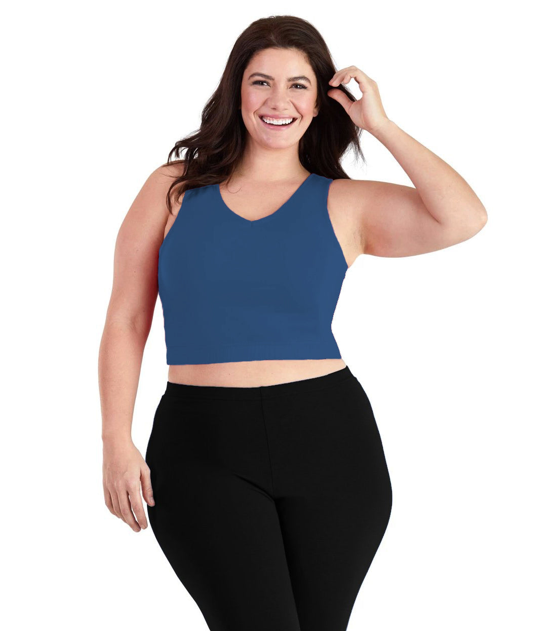 Plus size woman, facing front, wearing JunoActive plus size Stretch Naturals V-Neck Bra top in French Blue. The woman is wearing black JunoActive plus size leggings. Her left arm is up tucking her hair behind her ear, her right arm falls naturally to her side. 