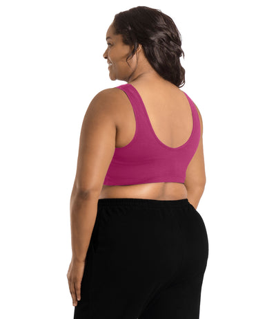 Plus size woman, facing back, wearing JunoActive Stretch Naturals Shirred Bra Top. Bra is gathered in middle on front and is a scoop top neck and scoops in back showing upper back. Straps are wide and bra color is merlot.