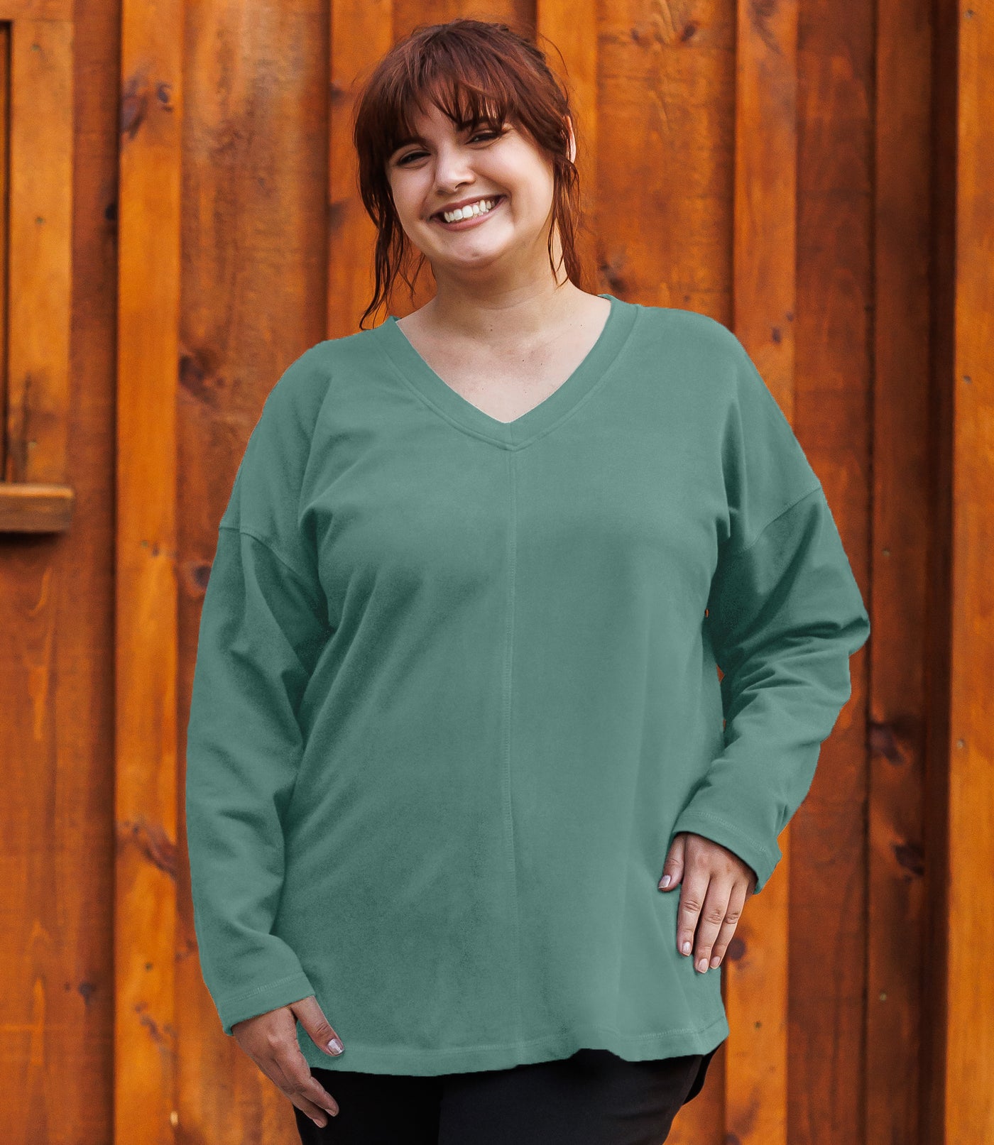Plus-size model, facing forward, wearing JunoActive's Mavie Drop Shoulder V-neck Tunic in Baltic Blue Green.