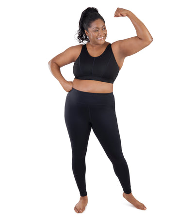 Bottom half of plus sized woman, frontview, flexing, wearing JunoActive JunoStretch Side Pocket Legging in black. The pants are full length and have pockets on each side.