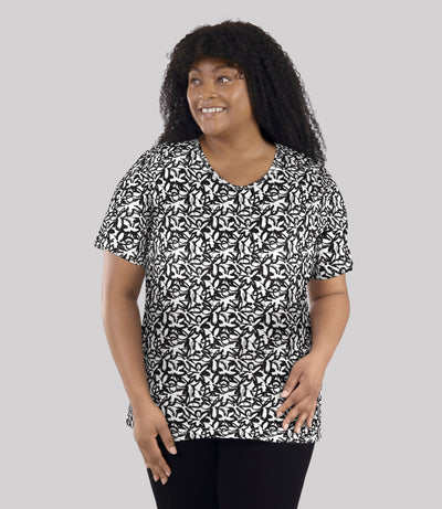 Model, facing front, wearing JunoActive's Junonia Lifestyle printed short sleeve neck top in color black and white wildflower print. 