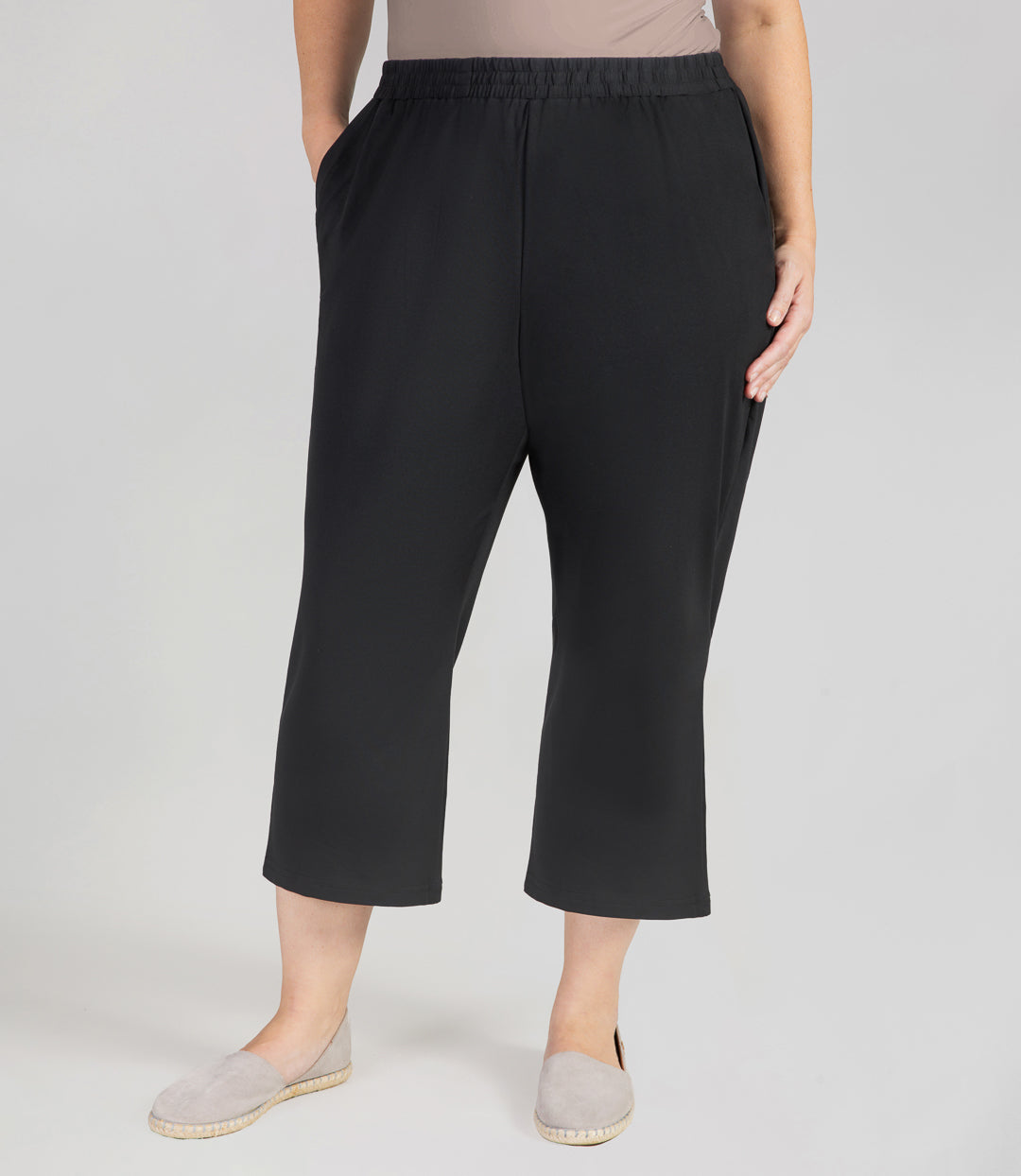 Front view, bottom half of plus sized woman, wearing JunoActives SoftWik Relaxed Fit Long Capris with Pockets in black. Hemline ends at mid-calf of model.