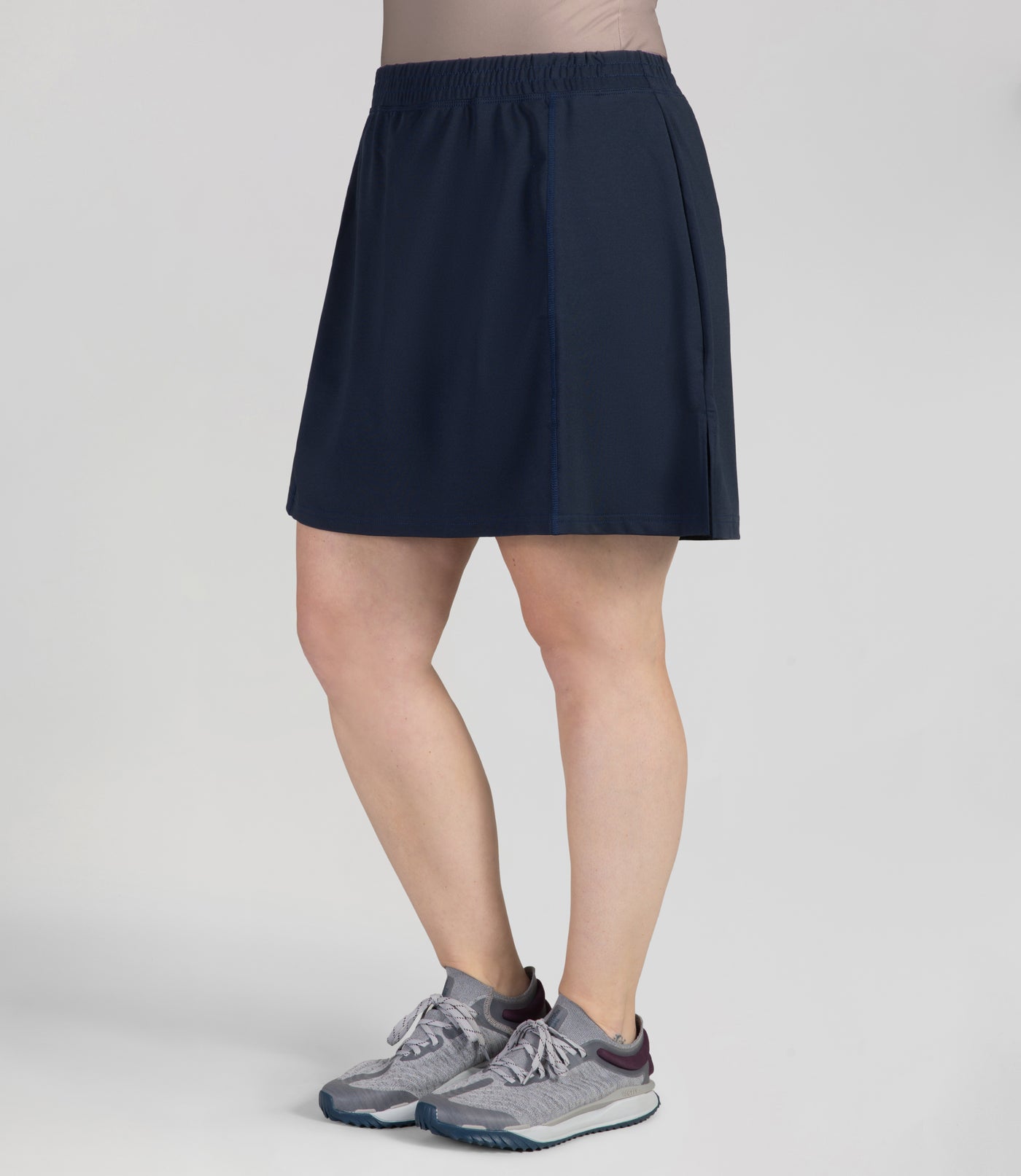 Bottom half of plus sized woman, Front side view, wearing JunoActives Quikwik lite skirted short in color navy. Skirt hem is a few inches above knee.