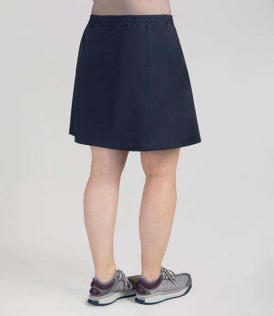 Bottom half of plus sized woman, back view, wearing JunoActives Quikwik lite skirted short in color navy. Skirt hem is a few inches above knee.