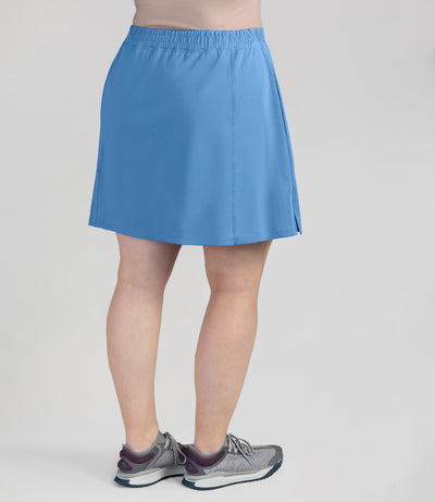 Bottom half of plus sized woman, back view, wearing JunoActives Quikwik lite skirted short in color columbia blue. Skirt hem is a few inches above knee.