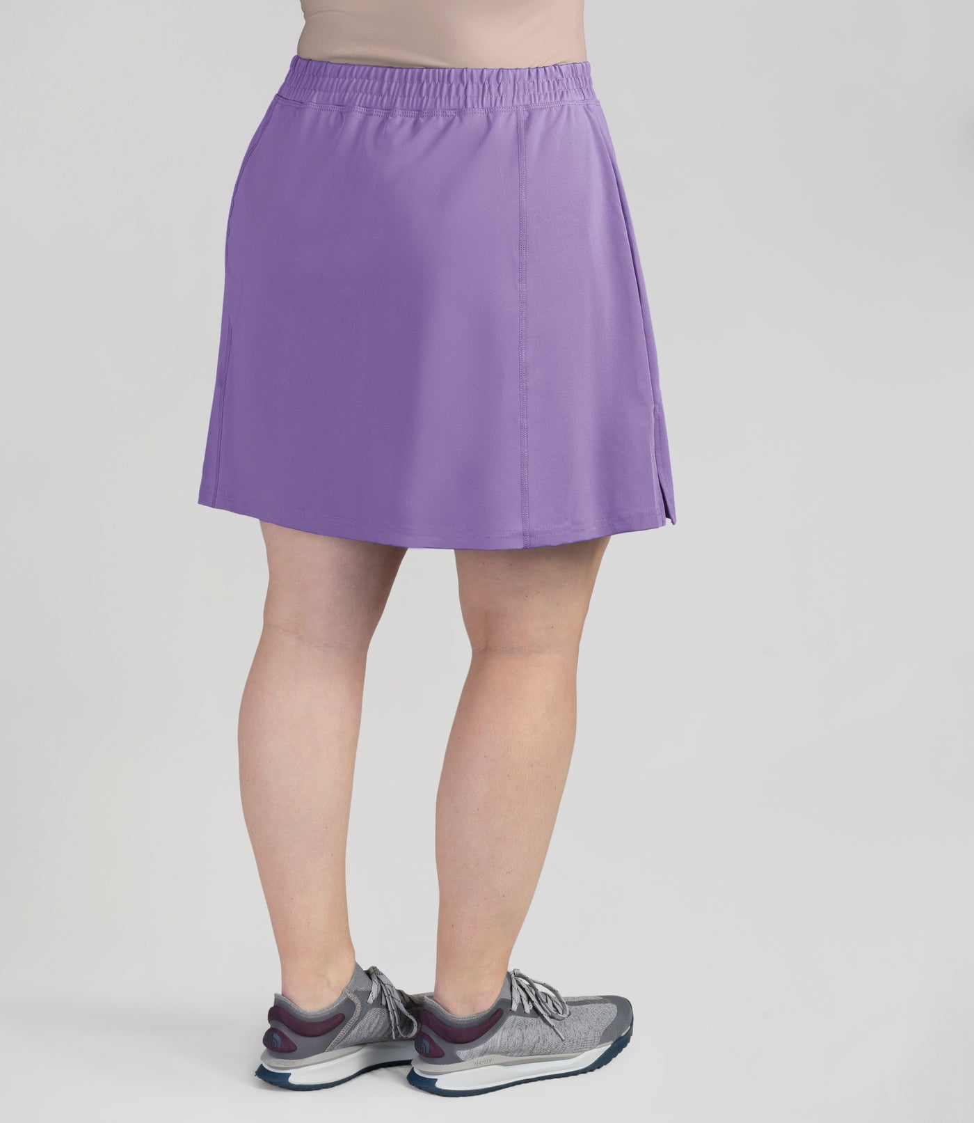Bottom half of plus sized woman, back view, wearing JunoActives Quikwik lite skirted short in color iris. Skirt hem is a few inches above knee.