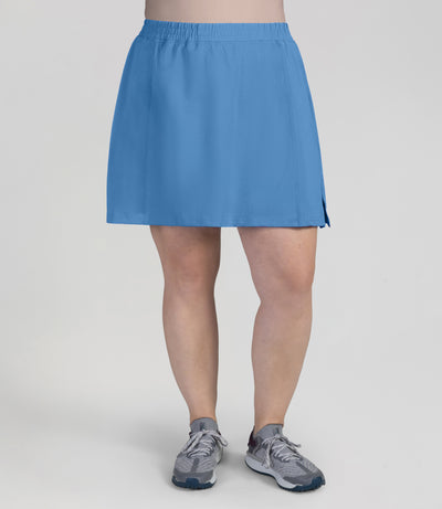 Bottom half of plus sized woman, front view, wearing JunoActives Quikwik lite skirted short in color Columbia blue. Skirt hem is a few inches above knee.