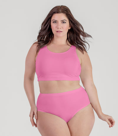 Plus size woman, facing front, wearing JunoActive plus size QuikWik Soft Control Bra Top in Power Pink.