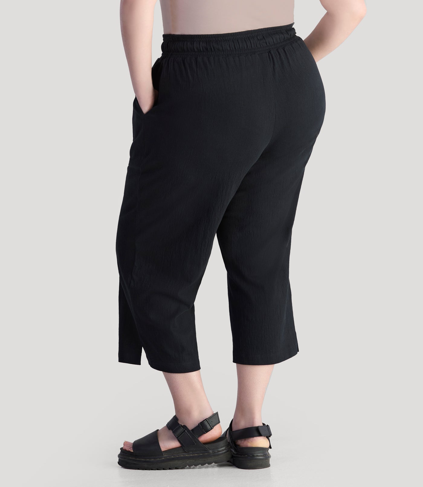 Plus size model, facing front, wearing JunoActive's EZ style cotton pocketed plus size capris in color black.