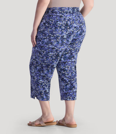 Plus size model, facing back, wearing JunoActive's EZ style cotton pocketed plus size capris in blue meadow print. 