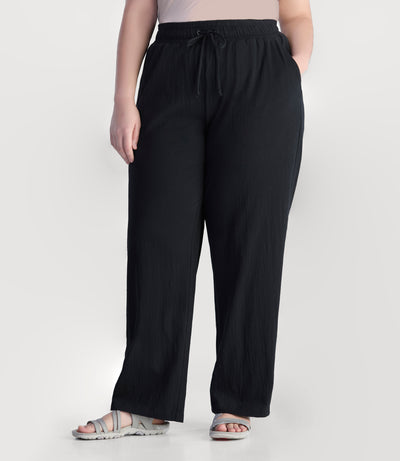 Plus size model, facing front, wearing JunoActive's EZ Style Cotton Pocketed plus size Pant in color black. Left hand in pocket of pant.
