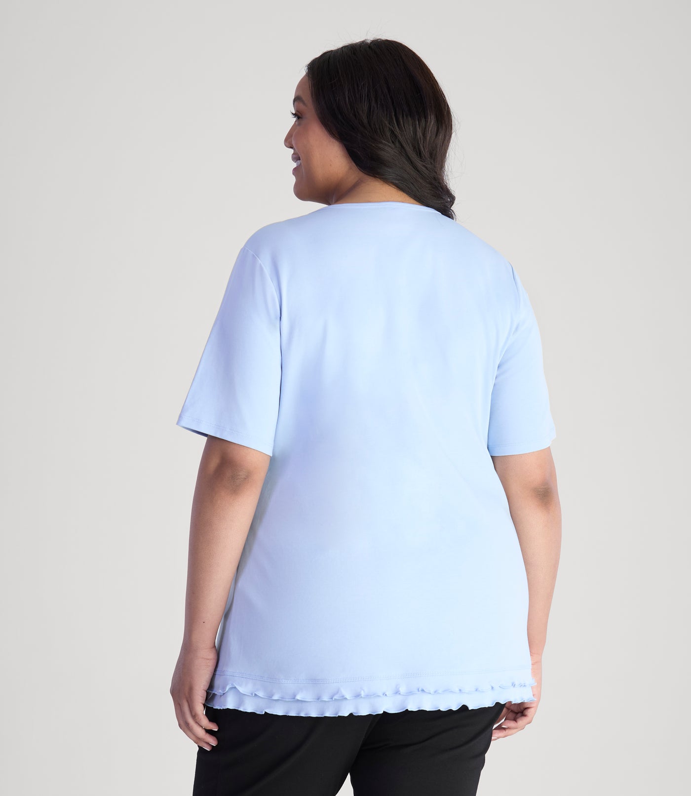 Model, facing back, wearing Cotton Chic Lettuce Trim Short Sleeve plus size Top in color sky blue.