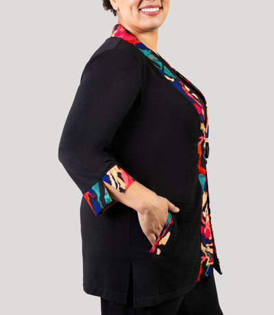 Plus size woman, facing side and close up, wearing a JunoActive's Junonia Classic Plus size cardigan featuring modern ikat print on lapels and cuffs with the reminder of cardigan solid black.