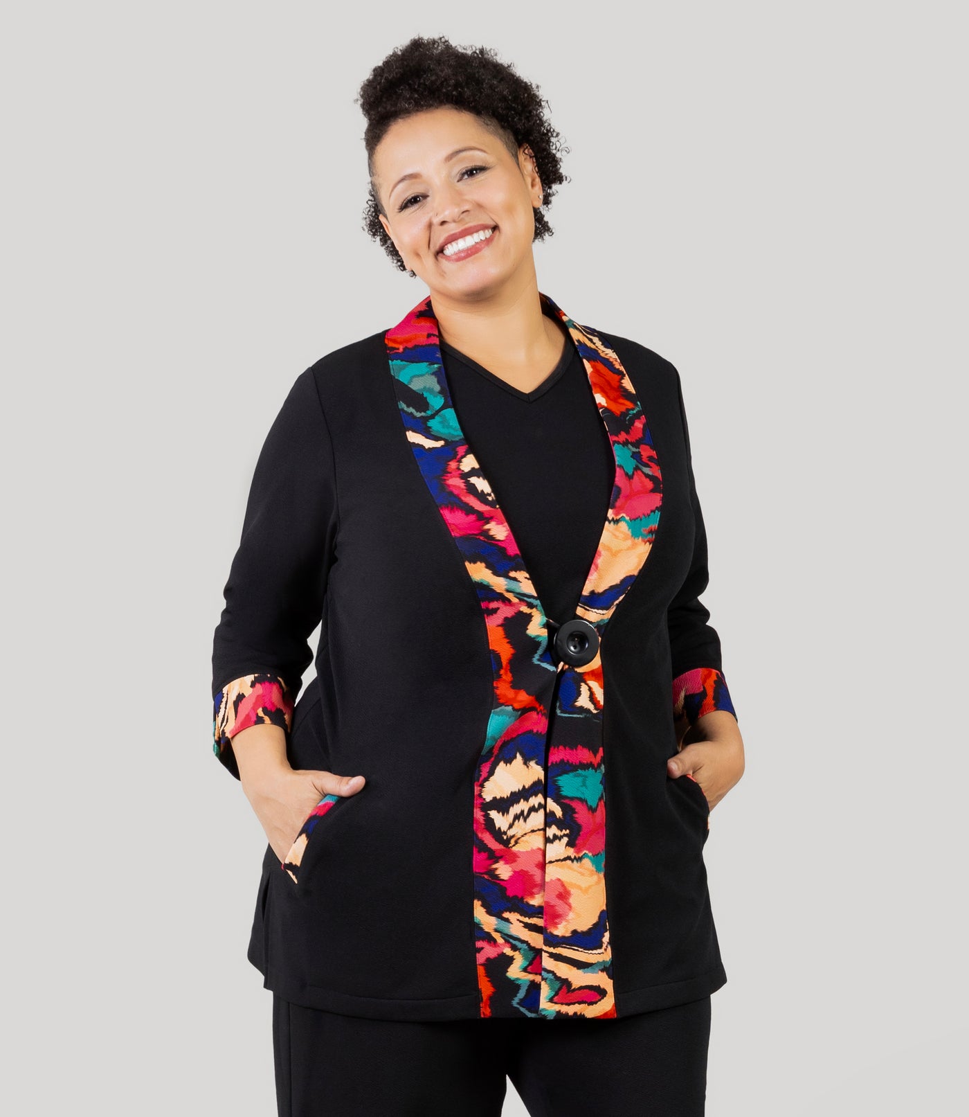Plus size woman, facing front, wearing a JunoActive's Junonia Classic Plus size cardigan with modern ikat print on lapels and cuffs with the rest of cardigan solid black.