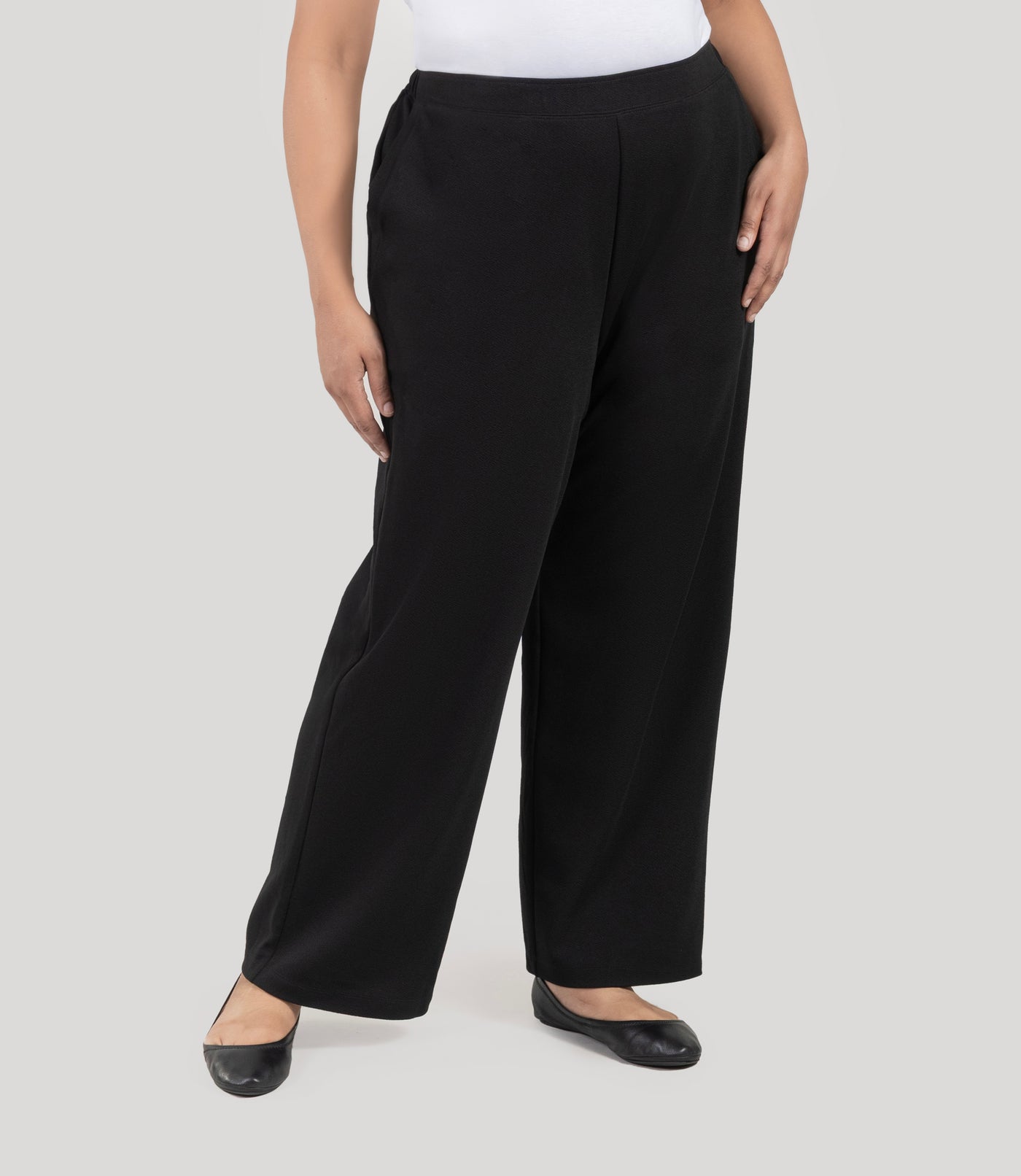 Plus size woman wearing JunoActive's Junonia Classic Pocketed black Plus Size pants on a plain background.