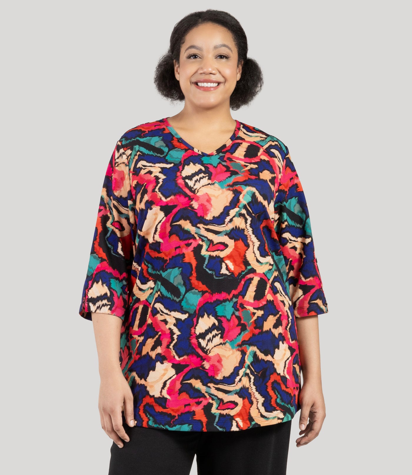 Plus size woman, facing front, wearing a JunoActive's Junonia Classic 3/4 Sleeve V-Neck Plus Size Tunic. Top features modern ikat print, v-neck, 3/4 sleeves and side vents at hem.