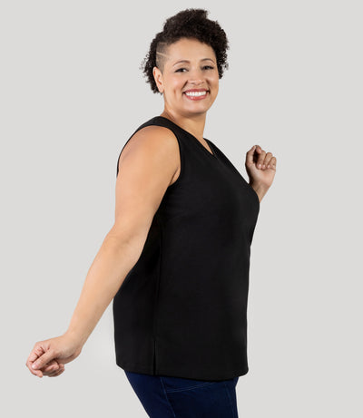 Plus size Woman, facing side, wearing JunoActive's Junonia Classic Sleeveless Plus Size Top in black, featuring v-neck and side vents.