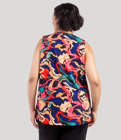 Plus size model, facing back, wearing JunoActive's Junonia Classic Sleeveless Plus Size Top in Modern Ikat print. Sleeveless top features v-neck and side vents at hem.