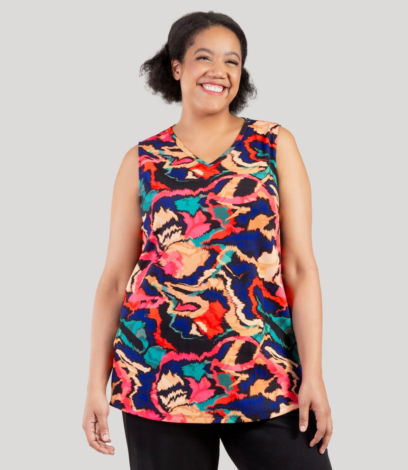 Plus size model, facing front, wearing JunoActive's Junonia Classic Sleeveless Plus Size Top in Modern Ikat print. Sleeveless top features v-neck and side vents at hem.