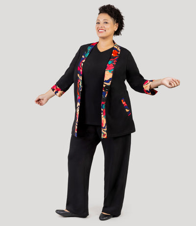 Woman wearing JunoActive Junonia Classic casual wear collection, featuring classic and colorful abstract pattern. She's wearing JunoActive's Junonia Classic Pocketed Black Plus Size Pant with Plus size cardigan.
