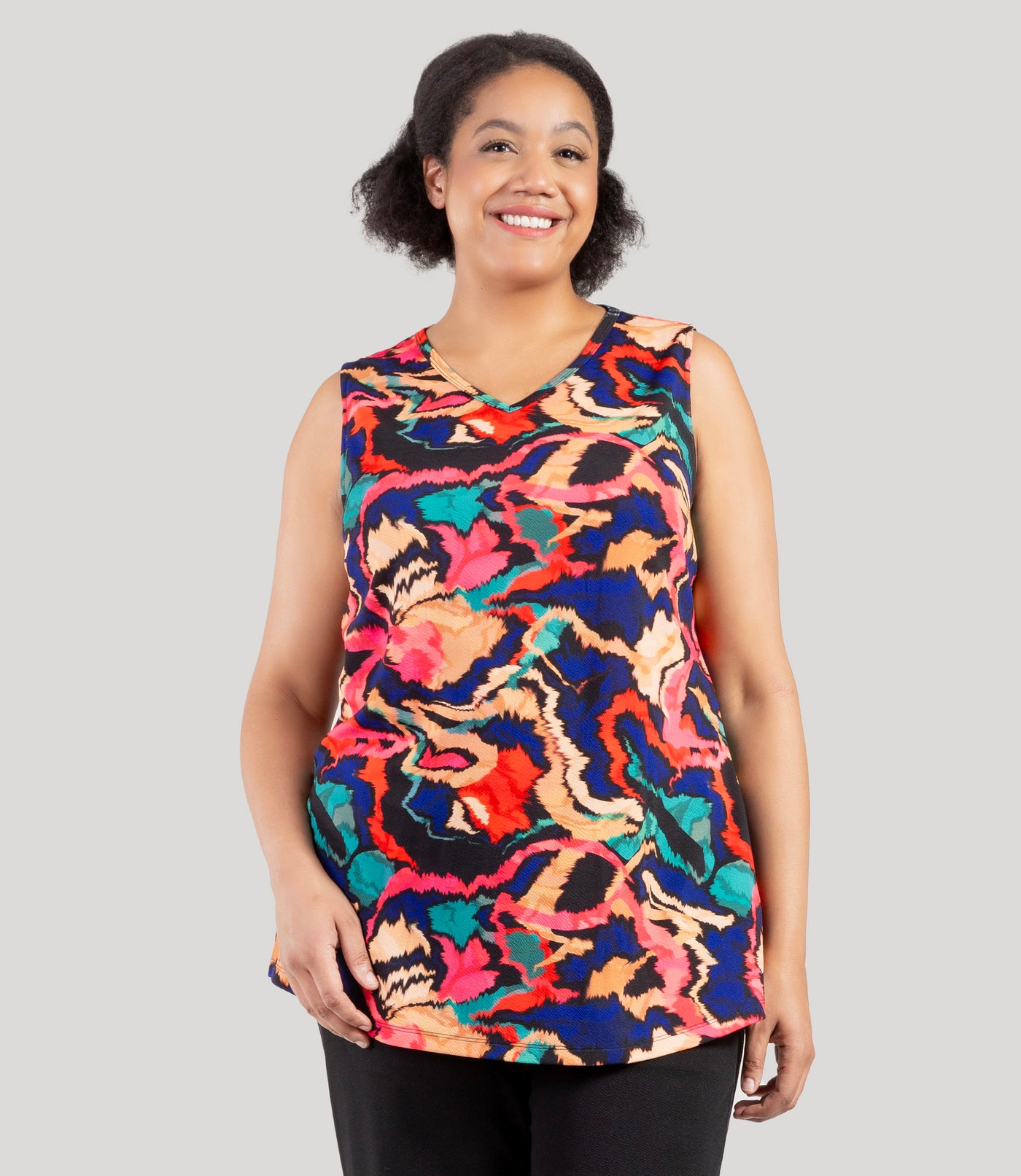 Plus size model, facing front, wearing JunoActive's Junonia Classic Sleeveless Plus Size Top in Modern Ikat print. Sleeveless top features v-neck and side vents at hem.