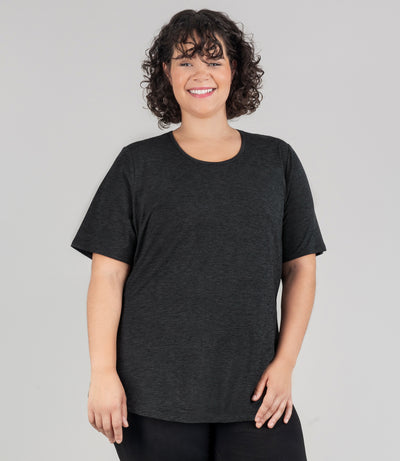 JunoActive model wearing soft supreme scoop neck short sleeve top in color heather black. Her arms are by her side. Length of sleeve is about 1.5 inches above elbow.