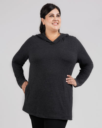 JunoActive model, facing front, wearing SoftSupreme Pocketed Hoodie in Heather Black. Her right hand is in the right pocket of top and left hard is on left hip.