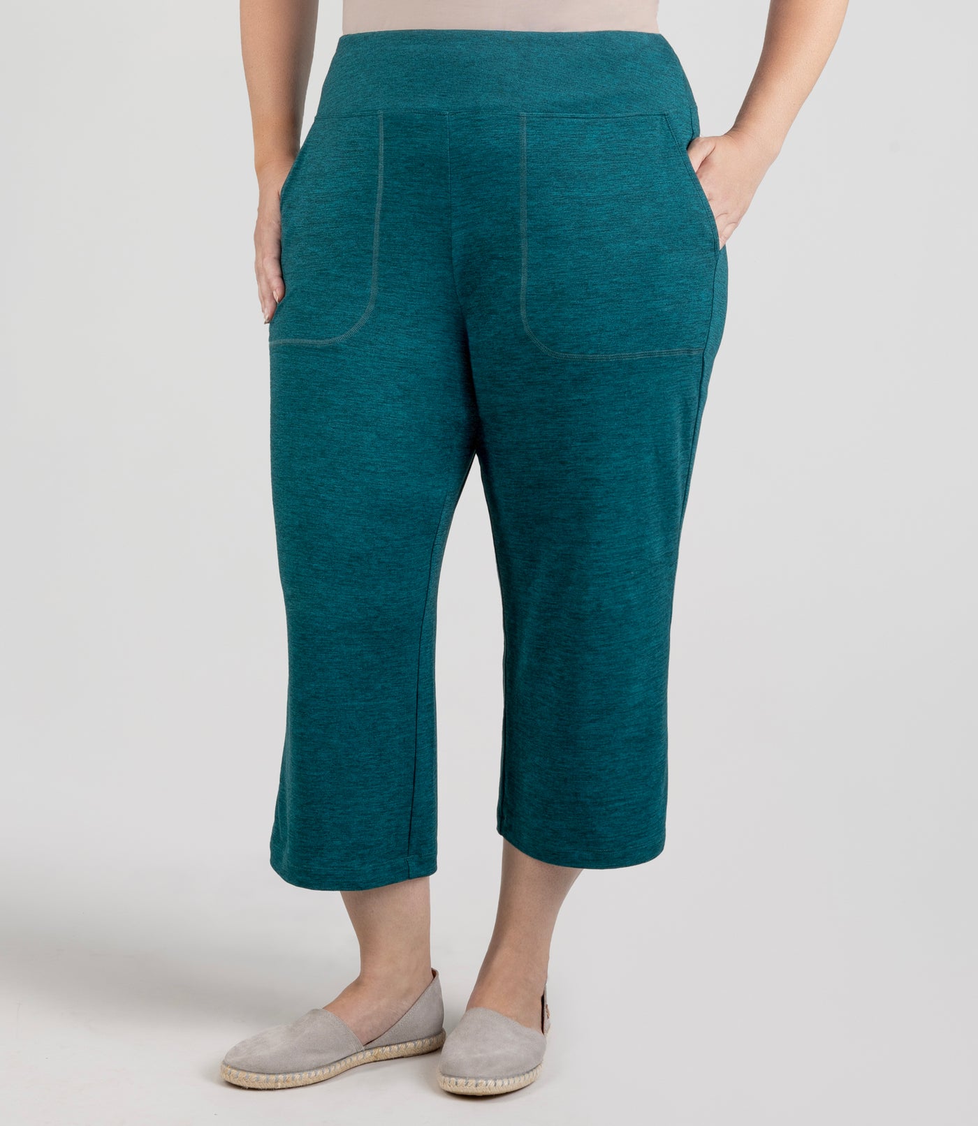 JunoActive model, wearing soft supreme pocketed lounge capri, in color heather dark teal, with both hands in pockets.